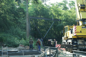 Das Stahlfachwerk für die Südfront des neuen Gebäudes wird von eiem großen mobilen Kran vom Transport gehoben und vorsichtig  zur Baustelle geschwenkt.