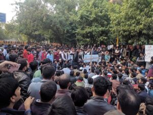 Studenten der Jamia Millia Islamia Universität (Neu-Delhi) protestieren zusammen mit Einheimischen gegen das neue Bürgerrechtsgesetz (CAA). Sie blockieren eine Straße, im Hintergrund der Aufmarsch der Polizei, Dez. 2019