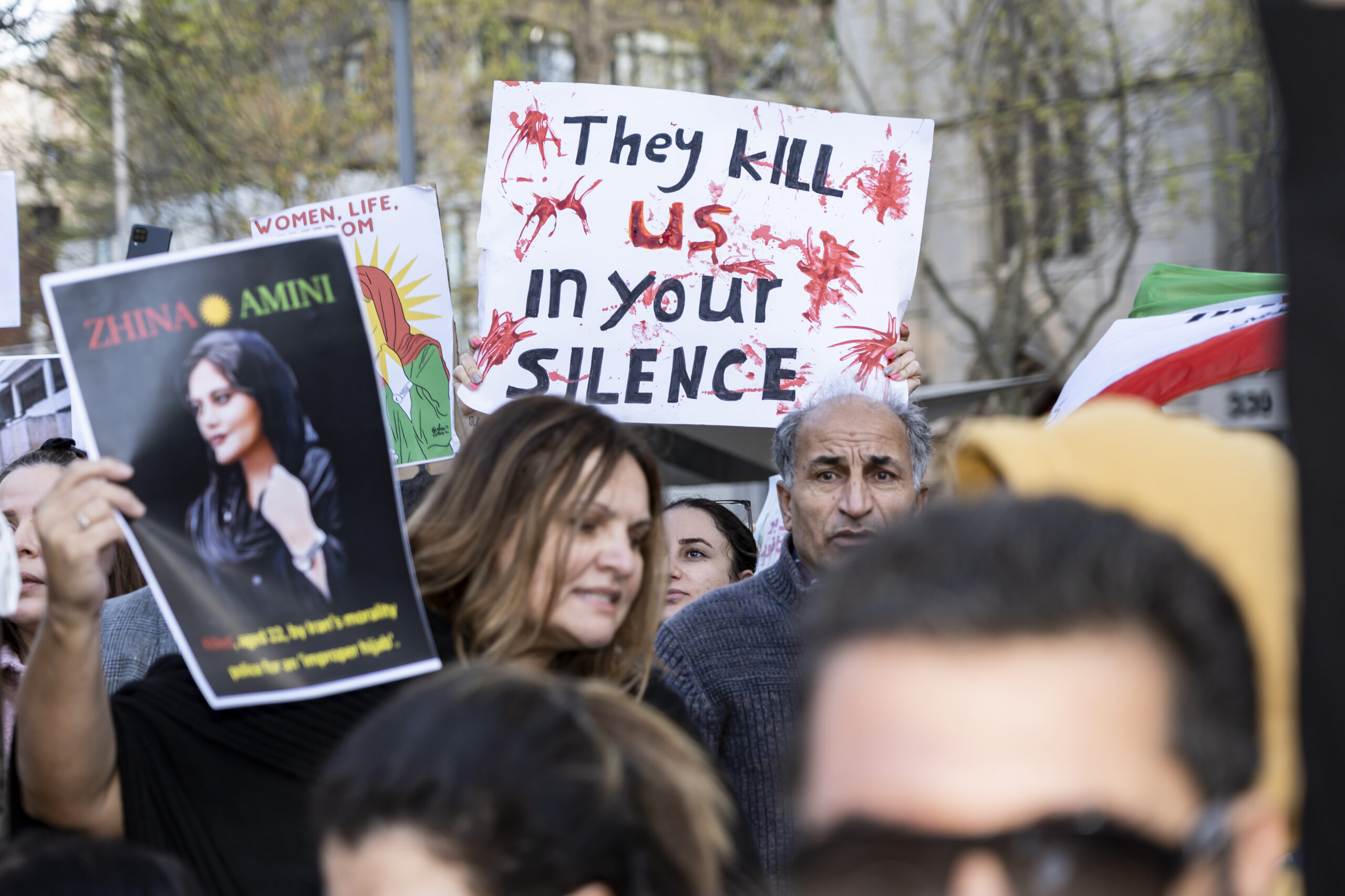 Mit ihrem Tod wird Mahsa Amini im Herbst zum Symbol für einen breiten Frauenwiderstand und Massenproteste in ganz Iran. Die brutale Gewalt, die sie erfuhr, will man/frau nun nicht mehr hinnehmen. Es kommt zu den längsten Protesten gegen das Regime im Iran seit 1979.
Solidaritskundgebungen für Jina Mahsa Amini gab es weltweit- hier: Melbourne 2022. Aus: wikipedia.
