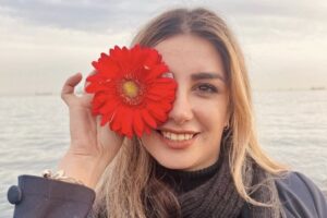 Tavaklian lächelnd, mit einer Blume vor ihrem zerstörten Auge.